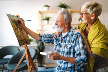 Portrait of smiling beautiful elderly couple painting