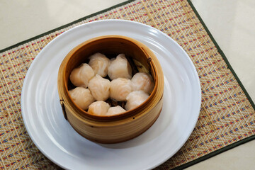 Asian steamed dish. Dim sum on a food shelves, various Chinese steamed dumpling in bamboo basket steamer in Chinese restaurants. with a chopstick