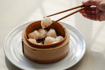 Asian steamed dish. Dim sum on a food shelves, various Chinese steamed dumpling in bamboo basket steamer in Chinese restaurants. with a chopstick