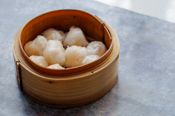 Asian steamed dish. Dim sum on a food shelves, various Chinese steamed dumpling in bamboo basket steamer in Chinese restaurants. with a chopstick