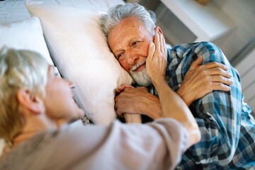 Happy senior couple embracing, sleeping together in bedroom