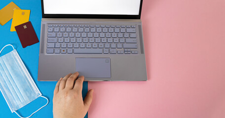 High angle shot of a laptop near cards and a face mask