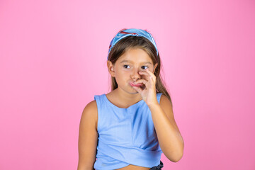 Young beautiful child girl over isolated pink background mouth and lips shut as zip with fingers....