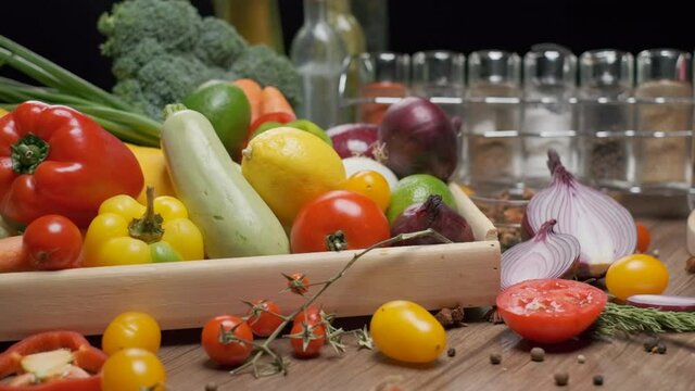 Fresh vegetables in wooden box on the kitchen table. Some chopped vegies on the front. Slow motion