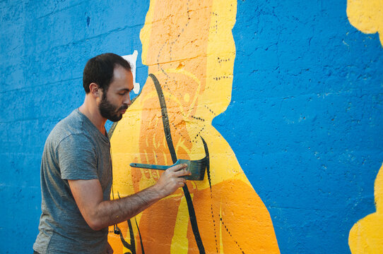 artist paints mural on a city street