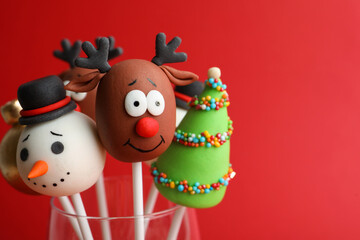 Delicious Christmas themed cake pops on red background, closeup