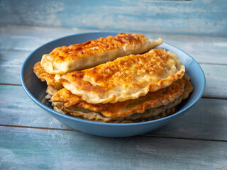 Fried pasties in a deep blue plate on a blue wooden tray