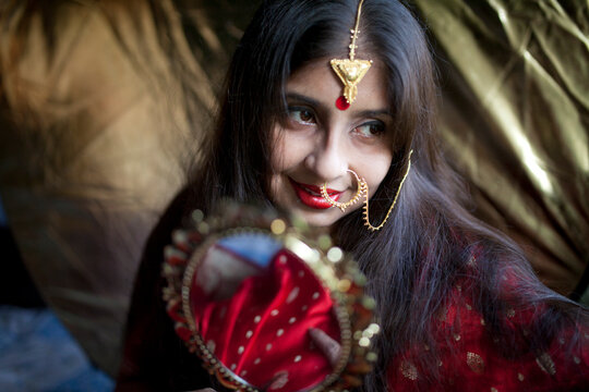 Young Indian woman with decorative Jewellery and golden Mirror