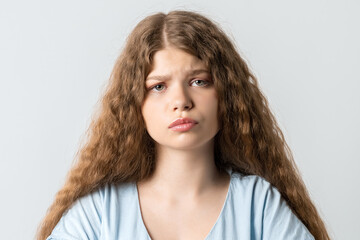 Naklejka premium Angry girl is looking into the camera with a piercing gaze. Studio shot white background. Facial expression concept
