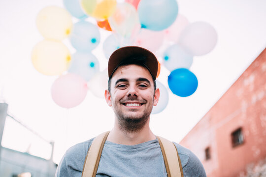 portrait of a young man with balloons behind
