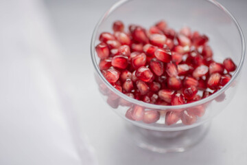 Pomegranate grain macro photography. Pomegranate seeds in a glass bowl close up. Peeled pomegranate in a transparent vase on the table. Ready-to eat.