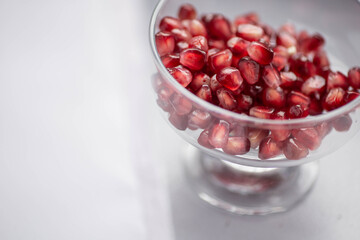 Pomegranate grain macro photography. Pomegranate seeds in a glass bowl close up. Peeled pomegranate in a transparent vase on the table. Ready-to eat.