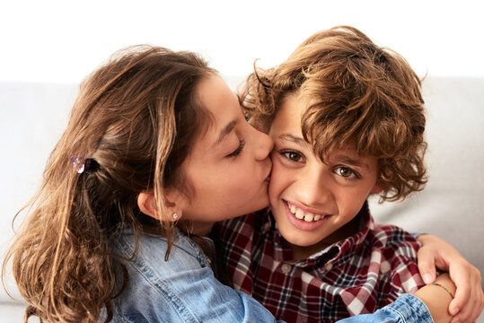 Sister kissing her brother in cheek.