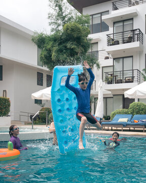 Young kid catapulted into the air using the inflatable in the swimming pool.