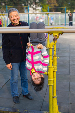 Senior Man teach his Granddaughter use parallel bars outdoor