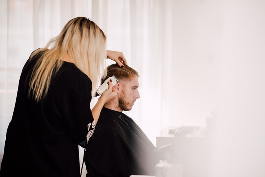 Young female hairdress giving a haircut to a customer at the studio