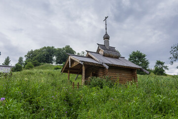 Mid summer . Fresh grass on the steep bank. A beautiful wooden chapel on the Protva river in Russia. Great place for tourism.