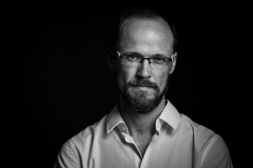 Black and white portrait of man in glasses looking concentrated in camera