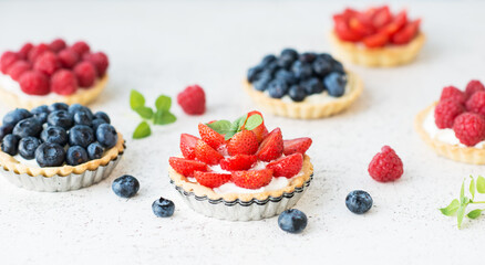 Sweet tarts with fresh summer berries, raspberries, strawberries and blueberries, selective focus - obrazy, fototapety, plakaty