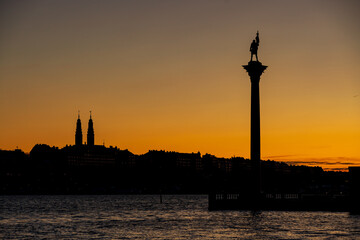 Fototapeta premium Crescent moon near the horizon. Behind the silhouette of the Stockholm skyline.