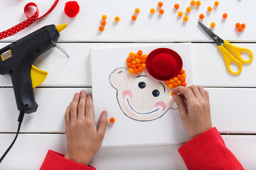Small child creates funny smiley portrait of clown. Crafts idea for children education concept. Top...