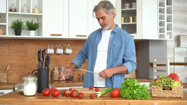 Man preparing to cook meat at kitchen, hands sharpening knife