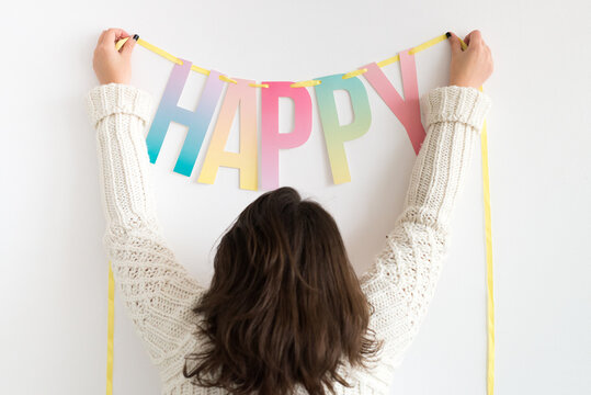 Young woman attaching Happy bunting on wall