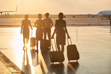 Bright evening sunlight in the airport and crew members walking - obrazy, fototapety, plakaty