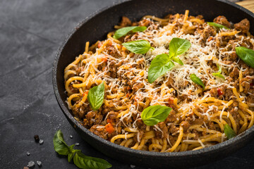 Pasta Bolognese in the skillet at black table.