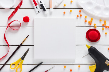 Workplace of the artist with collection of crafts equipment: canvas, pompoms, ribbon, brush, pen,...