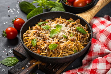Pasta Bolognese in the skillet at black table.
