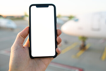 Mockup image of modern cell phone. Man Hand holding blank desktop screen mobile phone airport and airplane in the background. Travel concept remote work video call