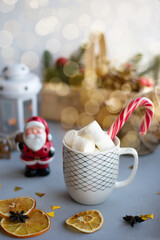 Obraz na płótnie Canvas Christmas drink, new Year still life. White mug with marshmallows, Santa Claus, lamp with candle. Holidays concept.