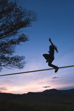 Man jumping on slackline with outstretched arms low angle view
