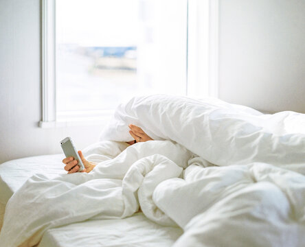 Person under blanket with smart phone