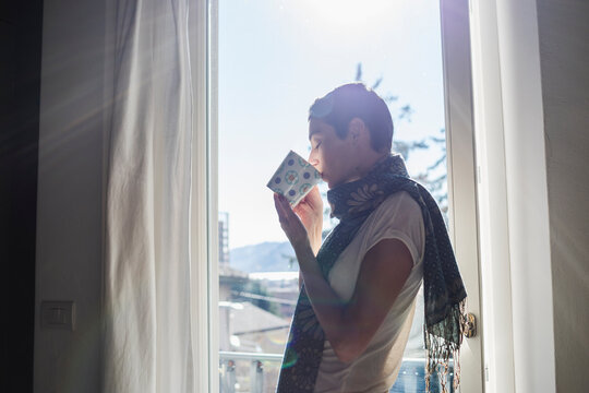 Brunette woman drinking a cup of coffee near the window