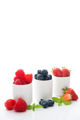 Fresh summer berries in glasses on a white background, strawberries, raspberries, blueberries, close-up