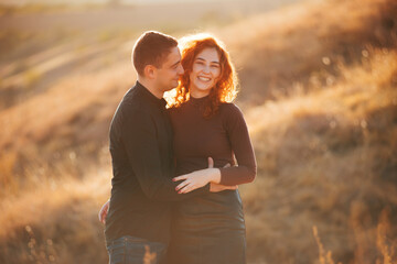 Photo of amazing cheerful couple embracing outdoor in sun light during sunset