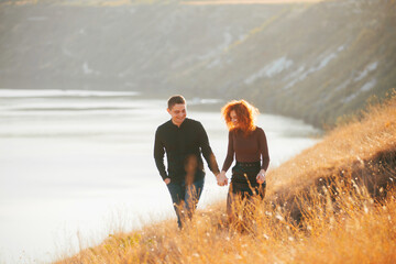 Photo of happy couple enjoying time together and walking on fields during sunset