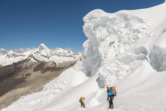 Alpinist standing under a dangerous snow cornice