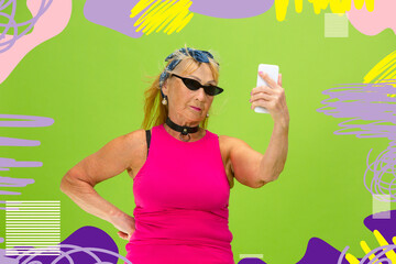 Forever young. Portrait of senior hipster woman using devices, gadgets isolated on orange studio...