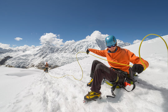 Mountain man giving rope to his fellow climbers