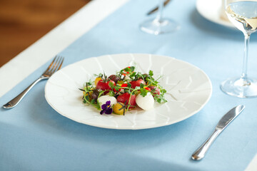 Tomato salad with herbs on the blue served table