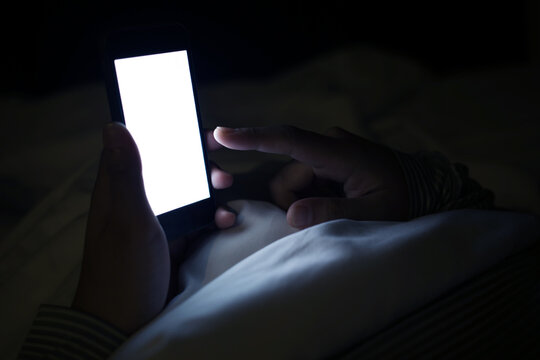 Female using smartphone on her bed in night