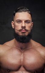 Fototapeta premium Brutal shirtless bodybuilder with black beard and mustache posing in dark studio background.