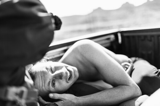 A shirtless young man rides in the back of a truck