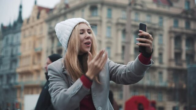 Pretty blonde woman taking selfie on phone on city background. Travel, happiness, xmas, holiday concept. Filmed on RED camera, 10 bit clolor