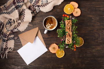 Natural Chirsmas decoration, cup of coffee, paper letter and craft envelope, pine cones, branches on dark rustic wooden background.