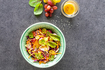 Fresh vegetable and fruit salad in a plate on a black stone background. Top view