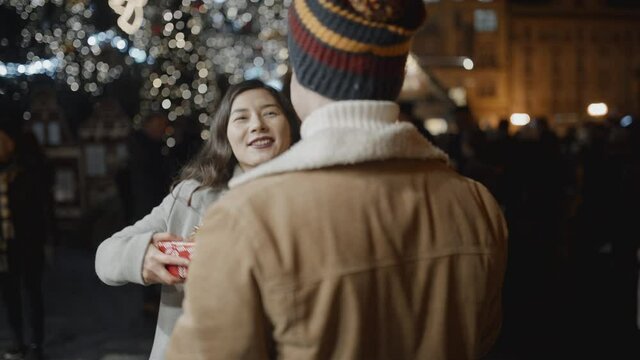 Man standing back to camera presents a xmas gift to her girlfriend, but she doesn't like it. Fail, christmas, new year, holiday concept. Filmed on RED camera, 10 bit clolor